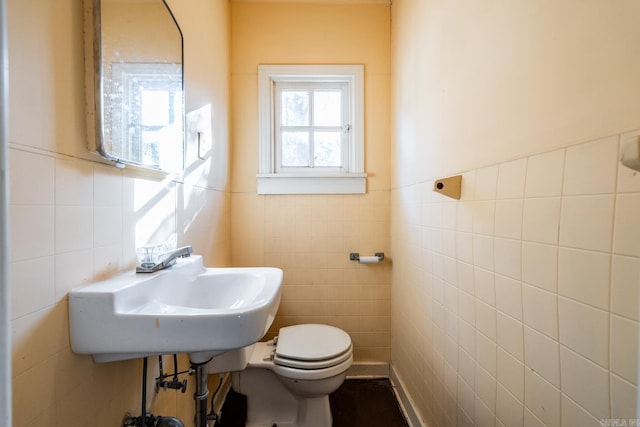 bathroom with toilet, tile walls, and sink