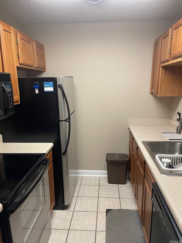 kitchen featuring a textured ceiling, black appliances, sink, and light tile patterned floors