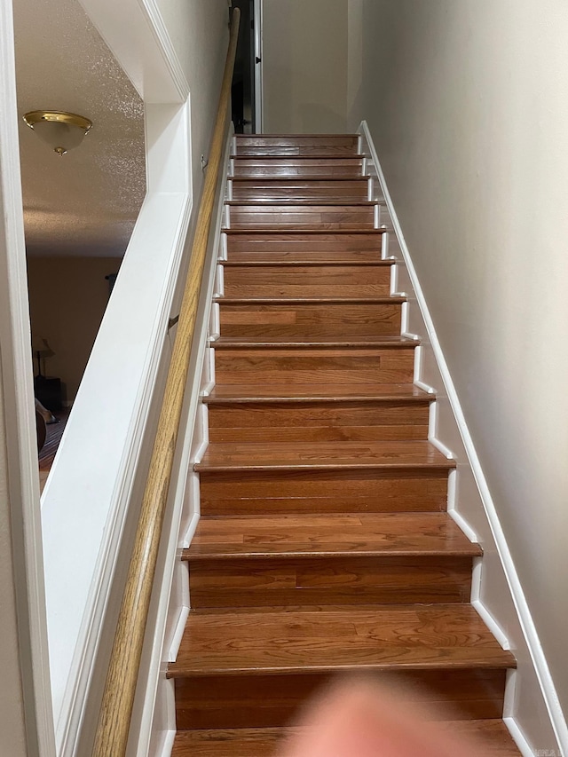 stairs with a textured ceiling and hardwood / wood-style flooring