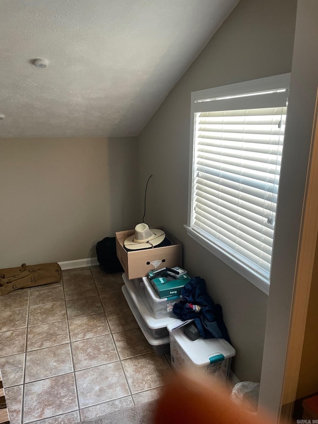 bonus room with vaulted ceiling, a textured ceiling, and light tile patterned floors