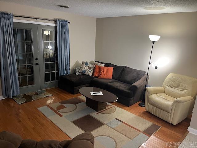 living room with a textured ceiling, french doors, and wood finished floors