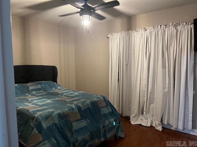 bedroom with ceiling fan, dark wood finished floors, and a textured ceiling