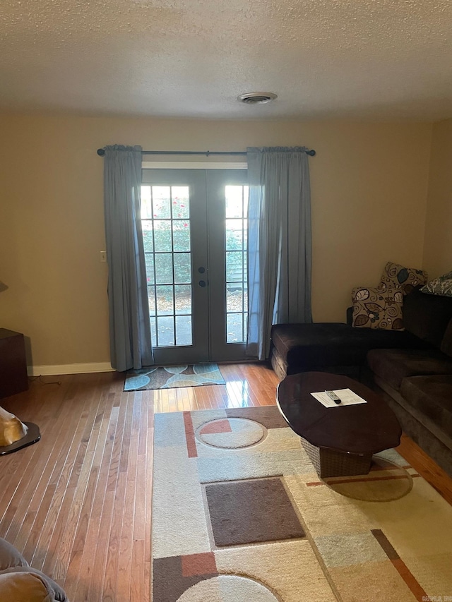 unfurnished living room featuring french doors, a textured ceiling, and light hardwood / wood-style floors