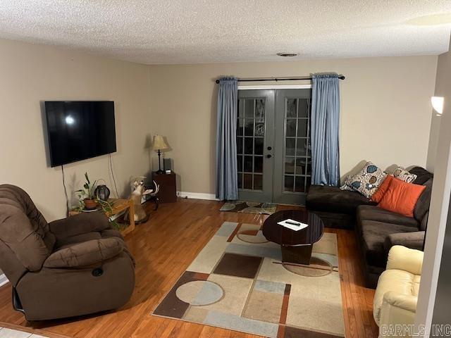 living room featuring a textured ceiling, wood finished floors, and french doors