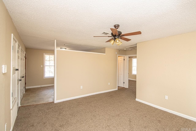 unfurnished room with a textured ceiling, carpet flooring, and ceiling fan