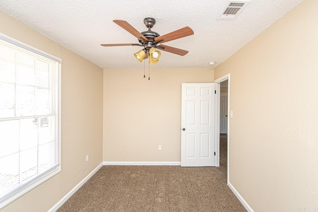 carpeted spare room featuring ceiling fan and a textured ceiling