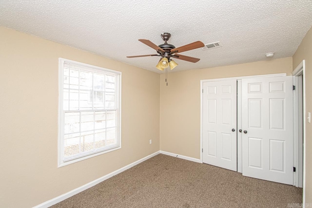 unfurnished bedroom with a textured ceiling, carpet floors, a closet, and ceiling fan