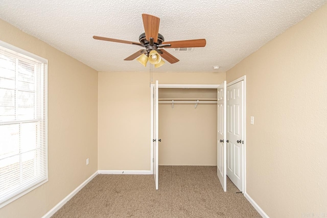 unfurnished bedroom with a textured ceiling, carpet floors, a closet, and ceiling fan