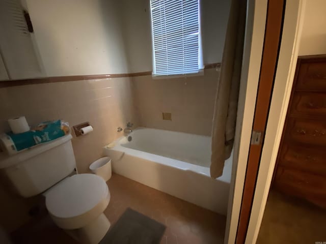 bathroom featuring tile patterned floors, toilet, tile walls, and a tub