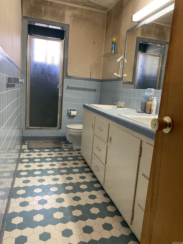 bathroom featuring vanity, toilet, a shower with shower door, and tile walls