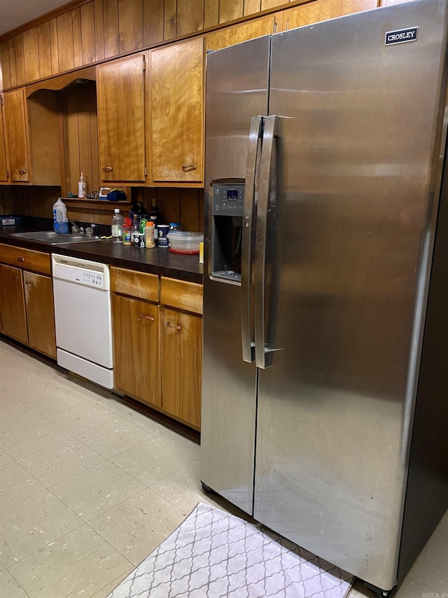 kitchen with dishwasher, stainless steel fridge with ice dispenser, wood walls, and sink