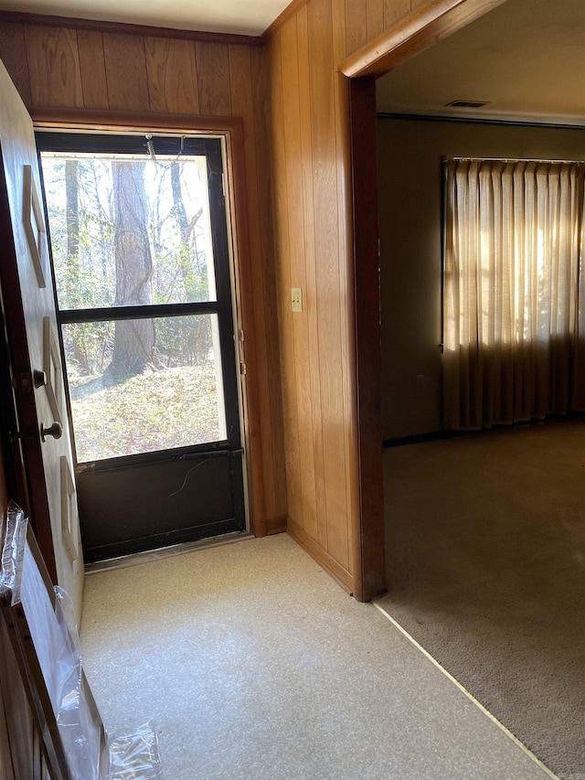 entryway featuring light carpet, a wealth of natural light, and wood walls