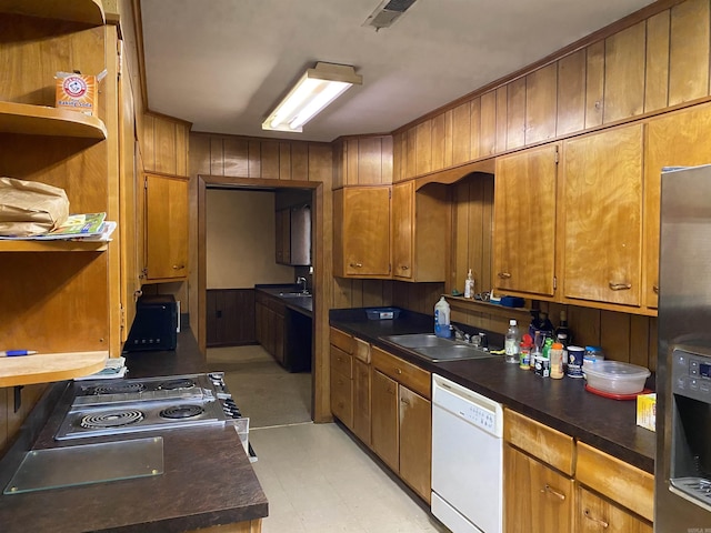 kitchen with stainless steel refrigerator with ice dispenser, stove, white dishwasher, and sink