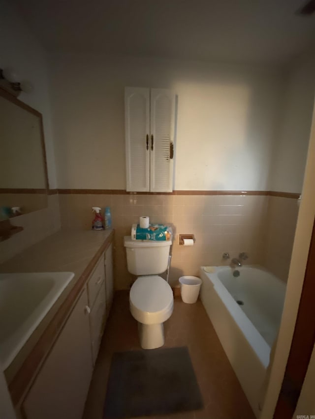 bathroom featuring a bathing tub, tile patterned flooring, toilet, vanity, and tile walls