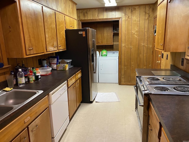 kitchen featuring electric range, sink, dishwasher, wooden walls, and washer and dryer