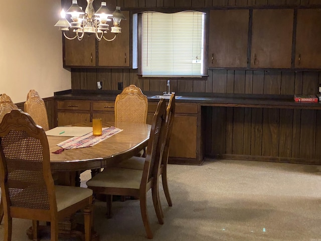 carpeted dining room with wooden walls and a chandelier