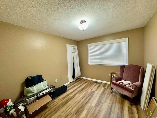 living area with a textured ceiling and light wood-type flooring