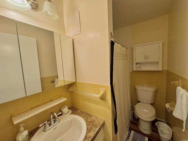 bathroom featuring toilet, tile walls, vanity, a textured ceiling, and walk in shower