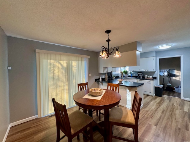 dining space with a textured ceiling, a chandelier, and light wood-type flooring