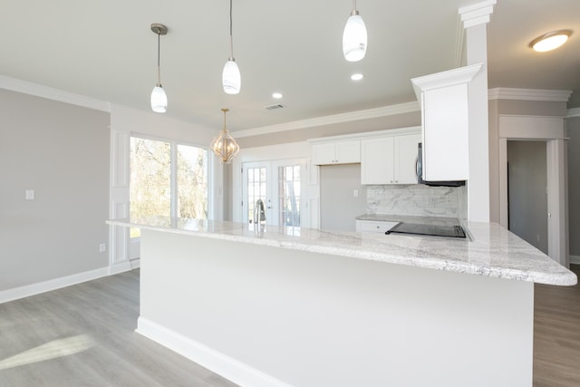 kitchen with pendant lighting, white cabinetry, backsplash, light stone countertops, and light hardwood / wood-style flooring