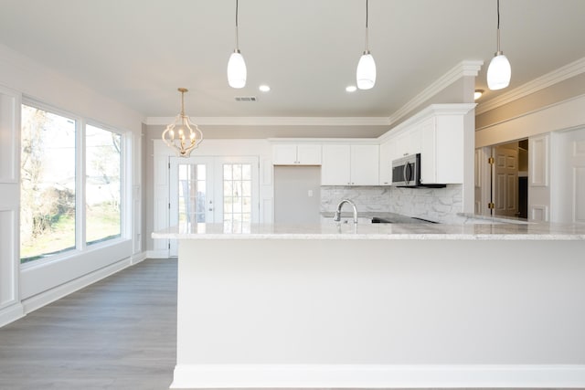 kitchen featuring white cabinetry, light stone counters, hanging light fixtures, and backsplash