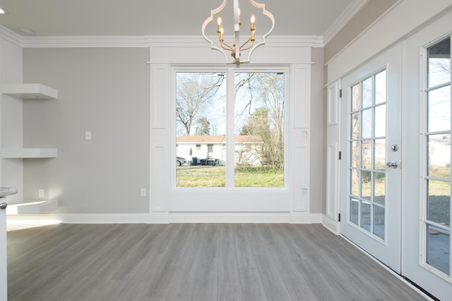unfurnished dining area with crown molding, hardwood / wood-style floors, and a notable chandelier