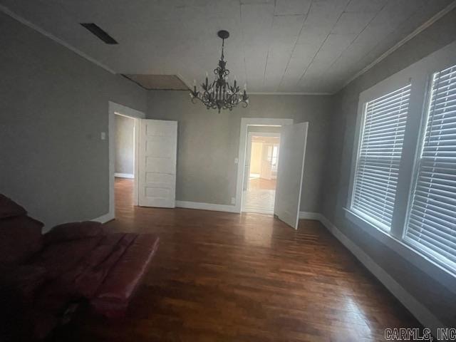 unfurnished dining area with ornamental molding, an inviting chandelier, and dark hardwood / wood-style flooring