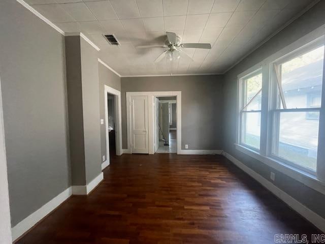 empty room with crown molding, ceiling fan, and dark hardwood / wood-style flooring