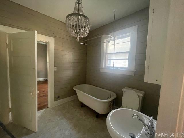 full bathroom with a chandelier, toilet, sink, wooden walls, and plus walk in shower