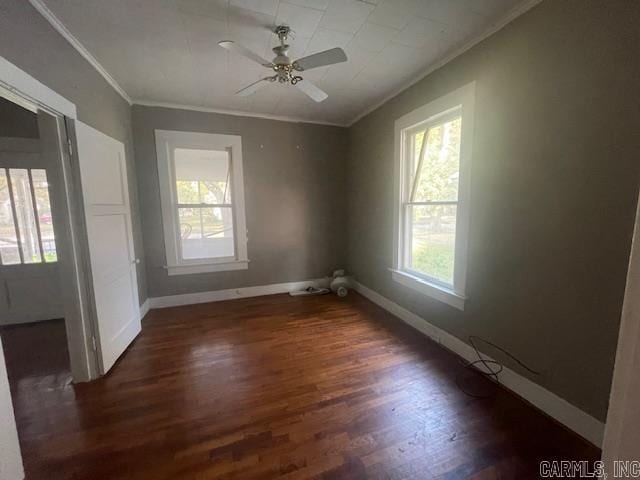 empty room with ornamental molding, dark wood-type flooring, and ceiling fan