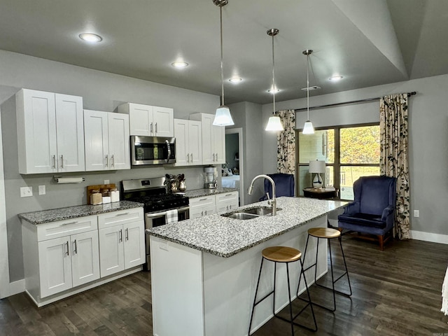 kitchen with white cabinets, stainless steel appliances, sink, and decorative light fixtures