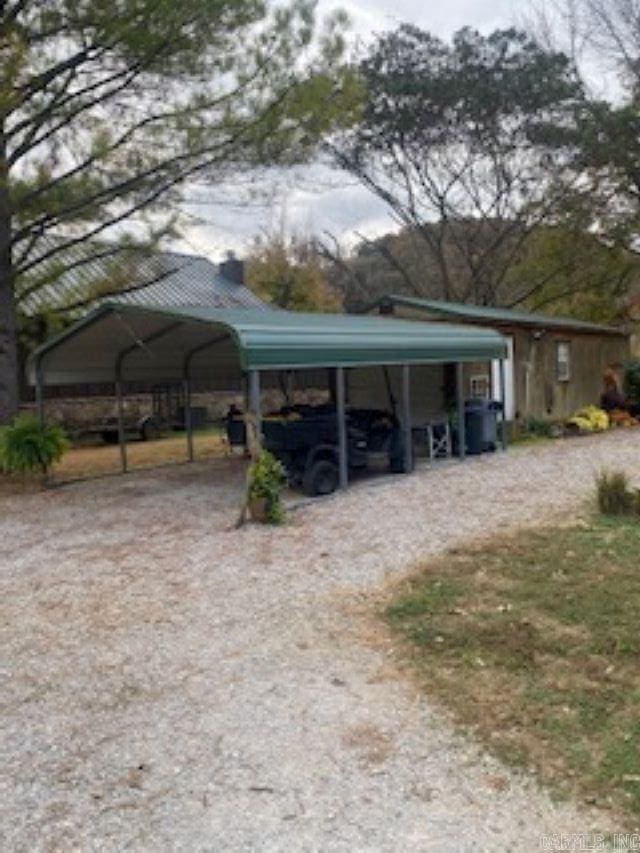view of car parking with a detached carport and dirt driveway