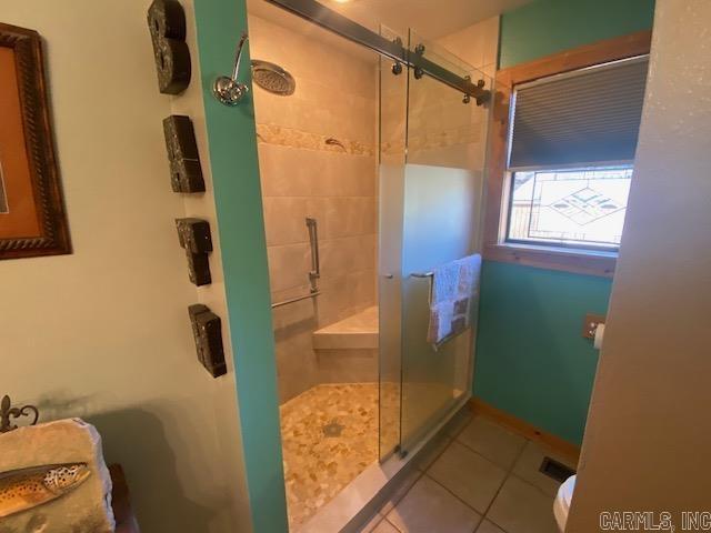 bathroom with tile patterned flooring, toilet, and an enclosed shower