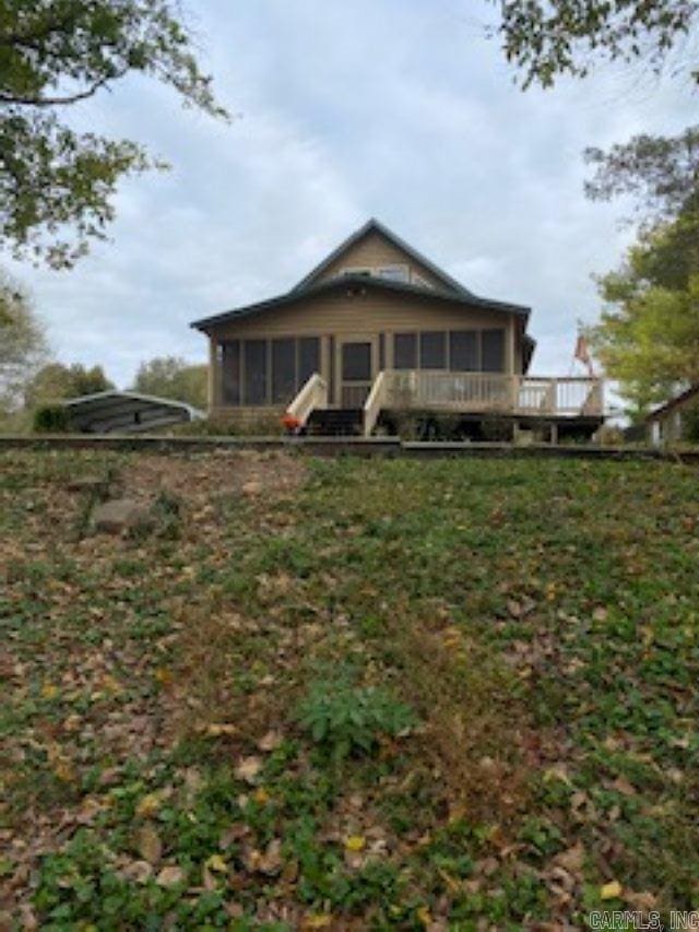 rear view of property featuring a sunroom and a deck