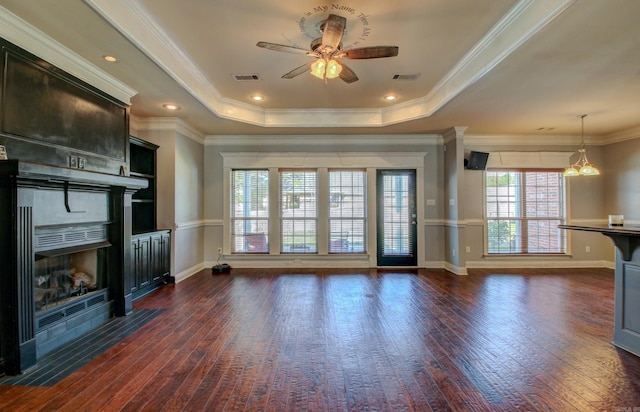 unfurnished living room with crown molding, ceiling fan, dark wood-type flooring, and a raised ceiling