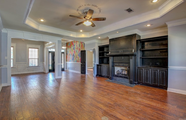 unfurnished living room featuring crown molding, a tray ceiling, and wood-type flooring