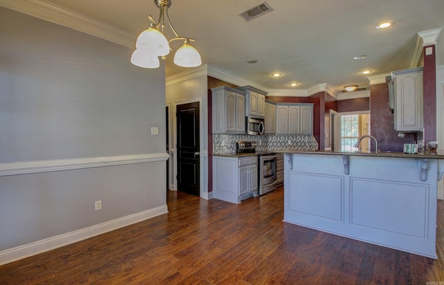 kitchen featuring dark wood-type flooring, crown molding, kitchen peninsula, and stainless steel appliances