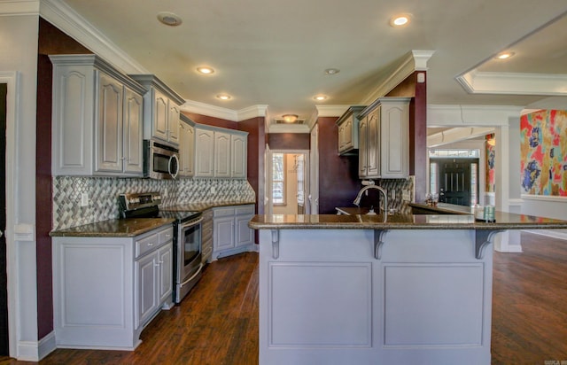 kitchen featuring kitchen peninsula, a breakfast bar area, dark hardwood / wood-style floors, gray cabinets, and stainless steel appliances