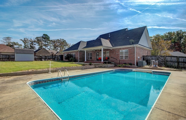 view of swimming pool featuring a yard, a patio area, and a storage unit