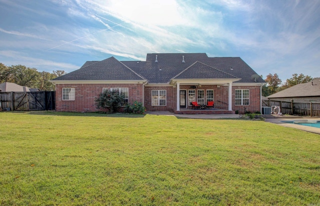 rear view of property featuring a fenced in pool, a patio area, a yard, and central air condition unit