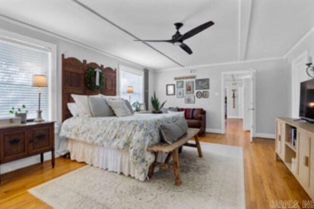 bedroom featuring hardwood / wood-style flooring, beamed ceiling, and ceiling fan