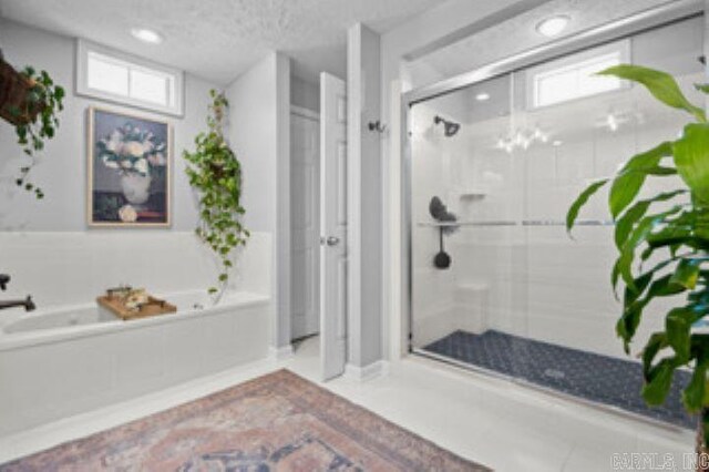 bathroom with a textured ceiling and shower with separate bathtub