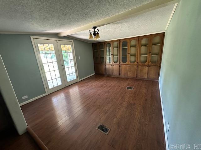 unfurnished living room featuring vaulted ceiling with beams, french doors, a textured ceiling, and dark hardwood / wood-style flooring