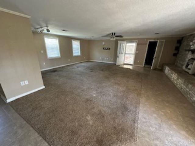 unfurnished living room featuring dark carpet, a large fireplace, and ceiling fan