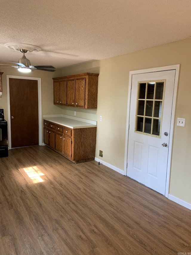 kitchen featuring a textured ceiling, ceiling fan, dark wood-type flooring, and black electric range