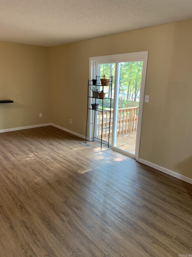 unfurnished room featuring dark wood-type flooring and a textured ceiling