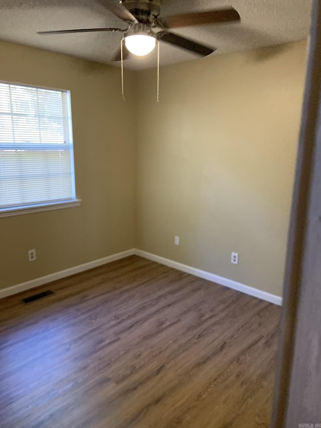 unfurnished room featuring a textured ceiling, ceiling fan, and dark hardwood / wood-style floors