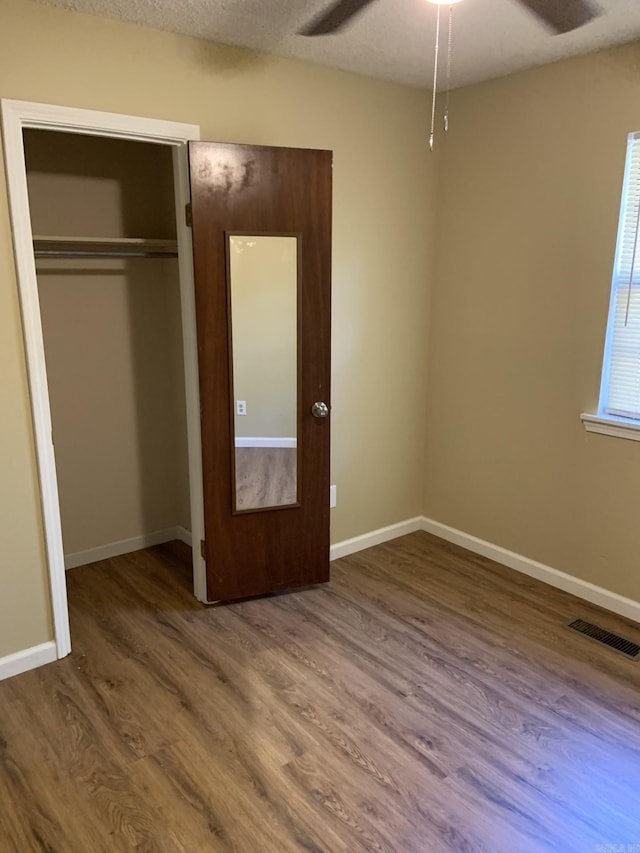 unfurnished bedroom featuring hardwood / wood-style floors, a textured ceiling, a closet, and ceiling fan