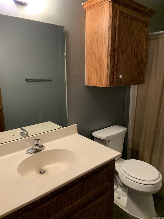 bathroom featuring a shower with shower curtain, vanity, and toilet