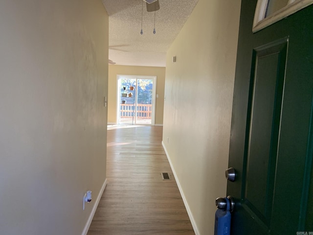 hallway with hardwood / wood-style floors and a textured ceiling